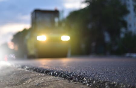 Thin layer of new asphalt close-up and road rollerの写真素材