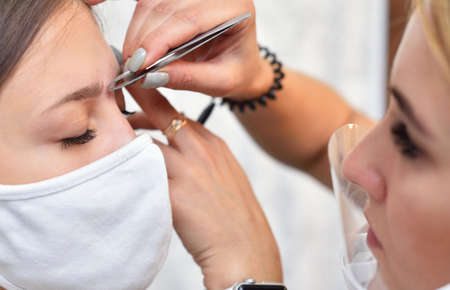 Young girl and beautician in protective masks at a beauty salon during the covid-19 pandemicの写真素材