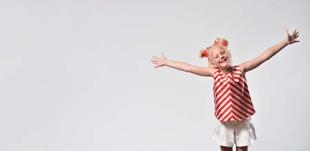 Child girl 7 years old smiling and opened her hands wide on a gray background with copy space