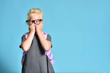 Young schoolgirl rubs her eyes from overworkの写真素材