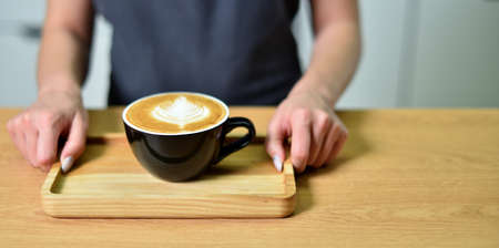 Female barista hands and a large cup of coffee with a pattern on the surface.の写真素材
