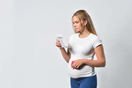 Pregnant woman reads instructions for taking pillsの写真素材