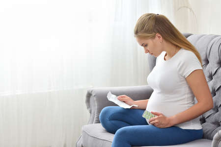 Pregnant woman reads instructions and holds pills