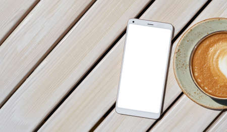 Smartphone with white screen on wooden table in cafeの写真素材