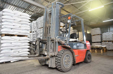 A forklift stands in a warehouse next to pallets with full bagsの写真素材