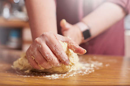 Close up of female hands kneading raw dough at home