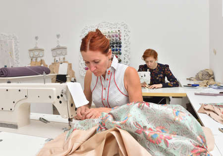 Two caucasian women seamstress at work on sewing machines in a sewing studio