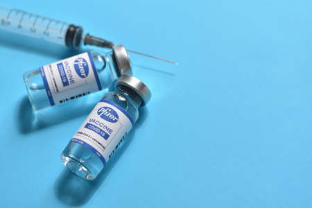 STARIY OSKOL, RUSSIA - NOVEMBER 23, 2020: Pfizer coronavirus vaccine concept and syringe on blue...