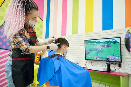 STARIY OSKOL, RUSSIA - NOVEMBER 6, 2020: Teenager boy in barber shop playing Minecraft gameのeditorial素材