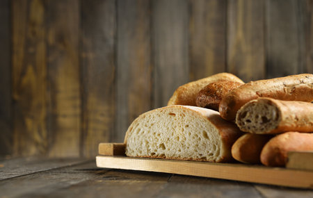 Cut different bread lies on a cutting board on a wooden backgroundの写真素材
