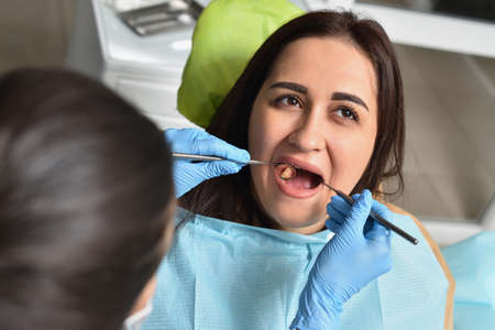 Dentist examines a womans teeth and looks for cariesの写真素材