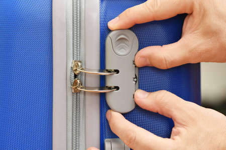 Male hands open the combination lock on the suitcase