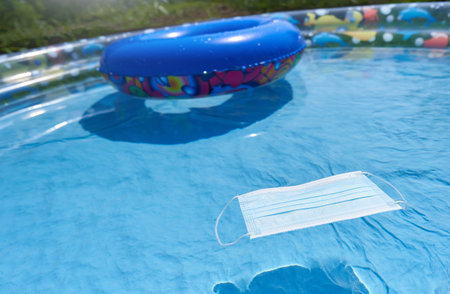 Protective mask in a childrens inflatable pool, the concept of a seaside holiday and the coronavirus...
