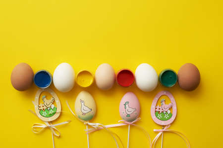 Easter template with chicken eggs and paints on a yellow background.