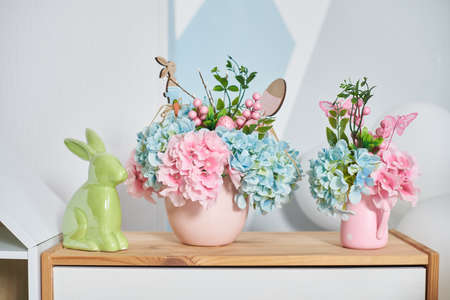 Easter decor with a hare and flowers on a wooden shelf in the interior.