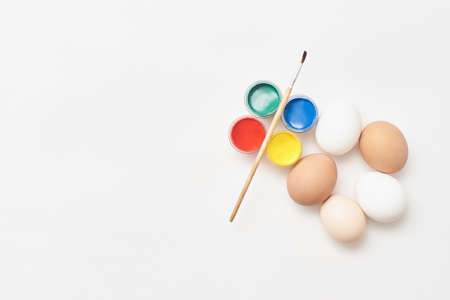 Chicken eggs and paints on a white backgroundの写真素材