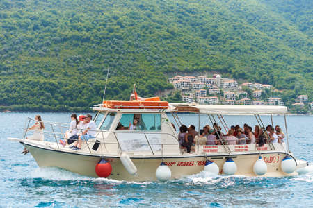PERAST, MONTENEGRO - JULY 20, 2021: Boat with tourists in the sea against the backdrop of mountainsのeditorial素材
