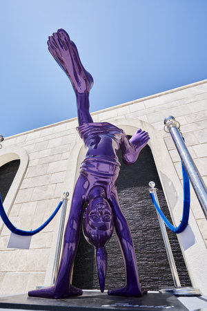 TIVAT, MONTENEGRO - JULY 15, 2021: Modern violet sculpture of a girl upside down on a city streetのeditorial素材