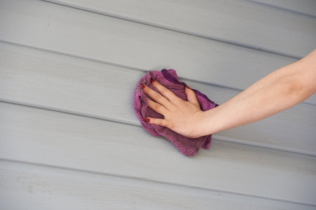 Female hand cleaning the exterior walls of a house made of plasticの写真素材
