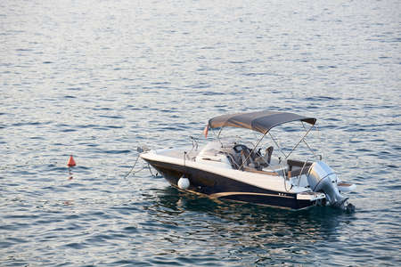 Small yacht with tent roof is moored in Kotor bay