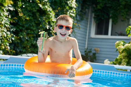 Joyful boy in pool drinking cocktailの写真素材