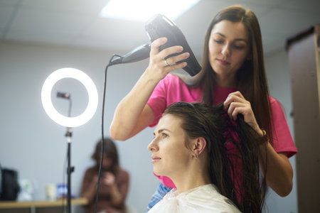 Hair stylist dries the clients hair with a hair dryerの写真素材