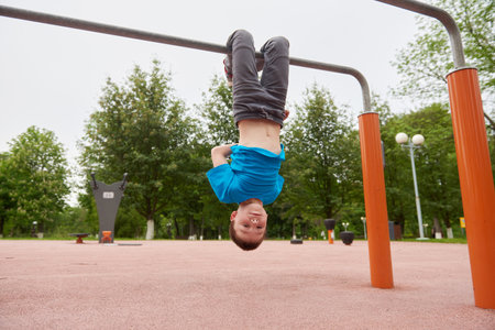 A boy is hanging upside down on a childrens playgroundの写真素材