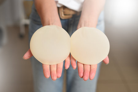 Woman showing breast augmentation implants in her handsの写真素材