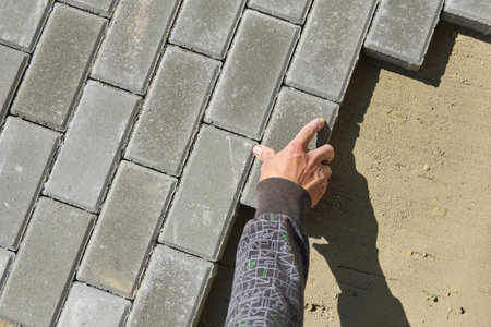 A worker lays paving slabs on the sand at a construction siteの写真素材