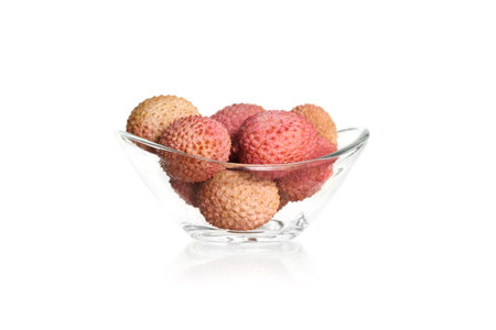Lychee fruits on a white background in a glass bowlの写真素材