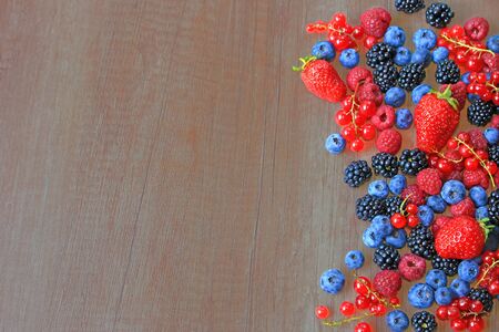 Mix of fresh berries on wooden background, strawberry, blueberry, raspberry, blackberry and red...
