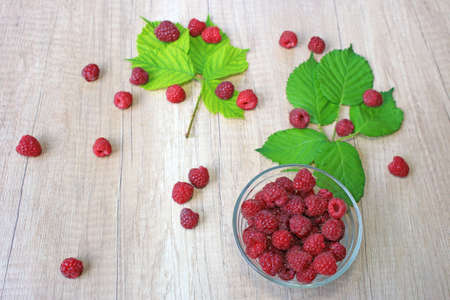 Fresh raspberries on wooden background, close up of berries juicy ripe fruit and leavesの写真素材