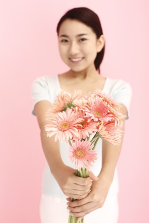 Woman smiling while holding flowersの写真素材