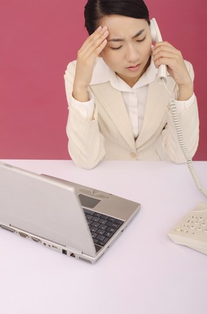 Woman talking on the phone, hand on her headの写真素材