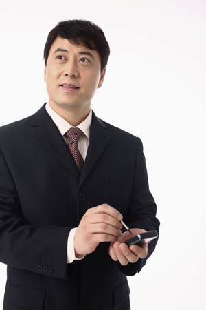 Businessman looking up while using PDA phoneの写真素材