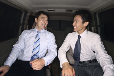 Businessmen chatting while traveling together in the car
