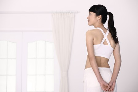 Woman standing with hands clasped behind her backsの写真素材