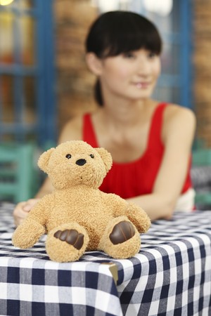 Teddy bear sitting on the table, woman in the backgroundの写真素材