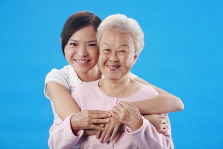 Woman hugging senior woman from the backの写真素材