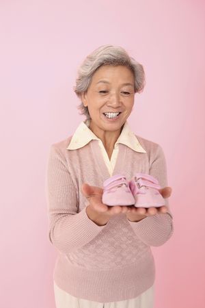 Senior woman holding baby shoes
