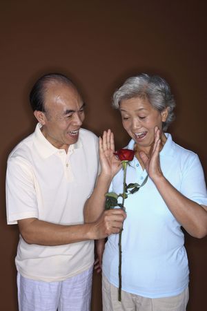 Senior man surprising senior woman with a roseの写真素材