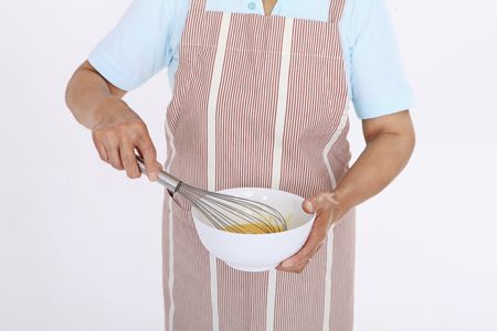 Senior woman beating eggs with whiskの写真素材
