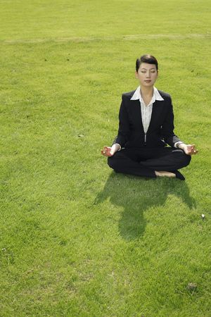 Businesswoman meditating on grassの写真素材