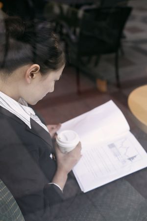 Businesswoman reading documents while having coffeeの写真素材