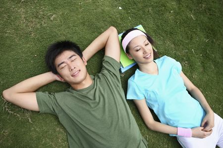 Man and woman relaxing on the field, eyes closedの写真素材