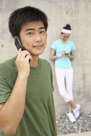 Man talking on the phone, woman text messaging on the phoneの写真素材