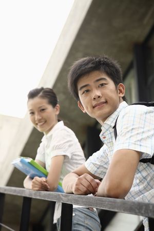 Man and woman standing on the stairs, smiling at the cameraの写真素材