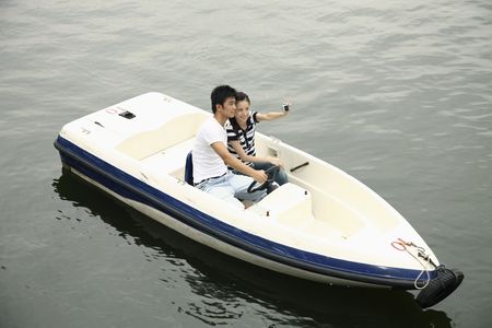 Man and woman taking picture together while traveling on the boatの写真素材