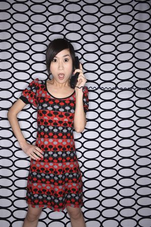 Woman looking shocked while talking on the phoneの写真素材