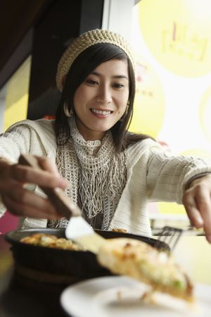 Woman serving pizza on a plateの写真素材